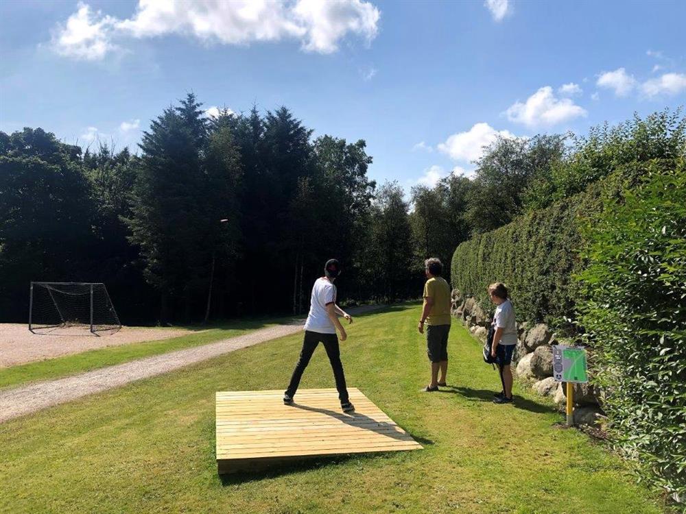To vaksne og eit barn som spelar frisbeegolf. Foto. - Klikk for stort bilete