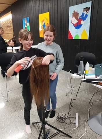 Jenter prøver seg som frisør på hårdukke. Foto - Klikk for stort bilete